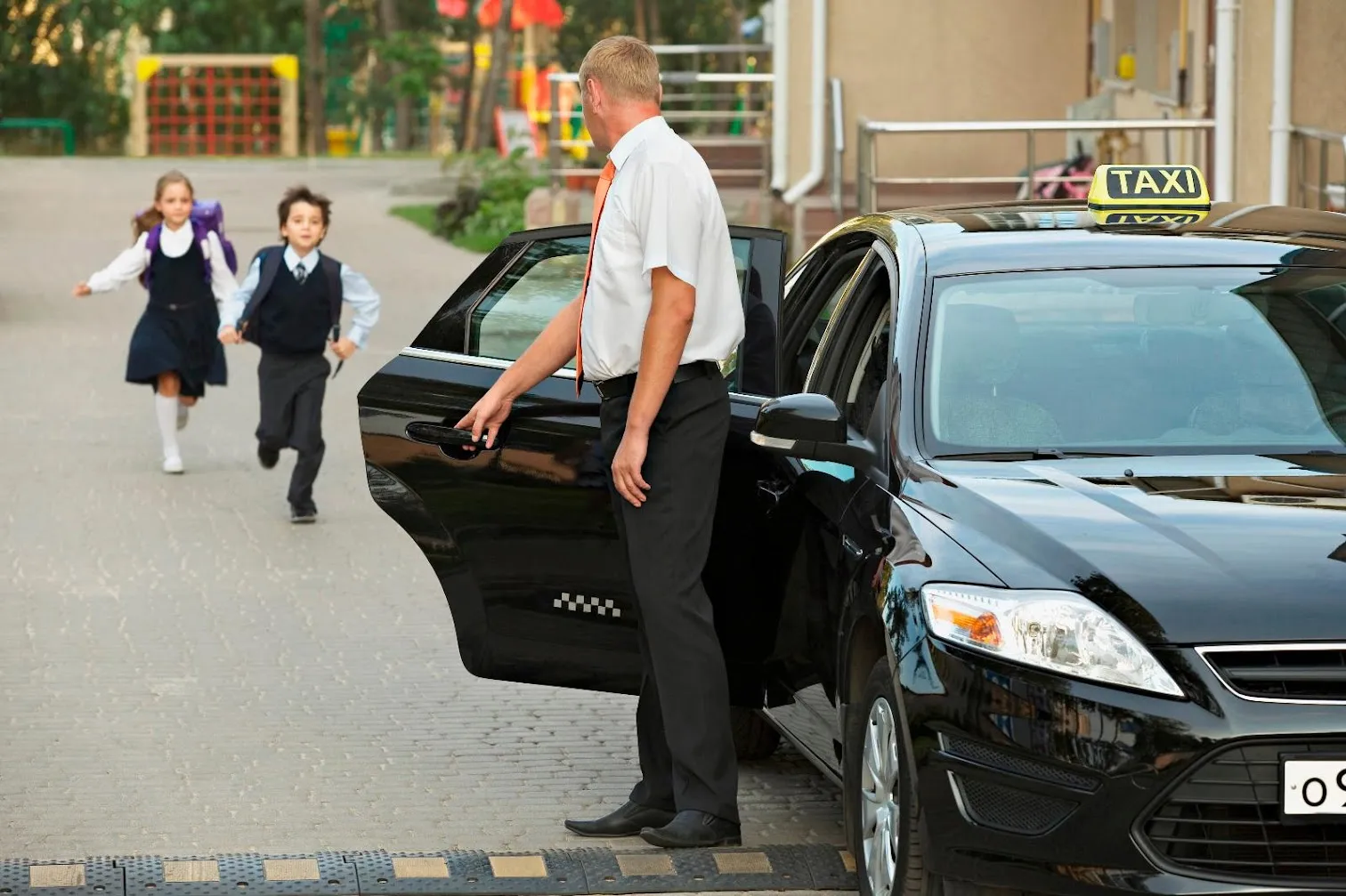 Chauffeur ouvrant la portière du taxi à deux enfants qui sortent de l'école